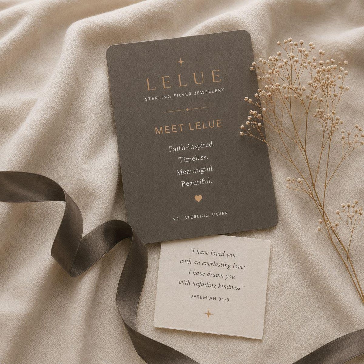 A LELUE card reading Faith-inspired, Timeless, Meaningful, Beautiful, beside a Promise Card with Jeremiah 31:3, on ivory linen with dried flowers